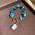 Detailed view of sea-style gold bracelet with blue stones and white pearl pendant - Blue Irregular Shell Bracelet
