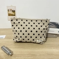 Retro-Kosmetiktasche aus beigem Cord mit schwarzen Punkten auf einem Holztisch - Khaki Punktiert