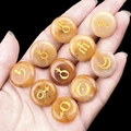 Handheld view of ten orange jade stones engraved with golden planetary astrology symbols - Yellow Jade / 10 Pieces Pack