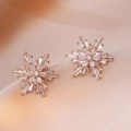 Macro view of gold-plated snowflake stud earrings with sparkling cubic zirconia inlay - Golden Elaborate Snowflake Style (E0870)