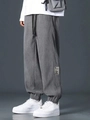 Detail view of grey corduroy joggers with printed patch on the hem and elastic cuffs - Gray