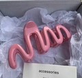 Close-up of pink wave-shaped hair claw clip with glossy finish in aesthetic packaging - Rose Pink
