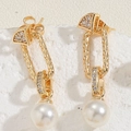 Macro detail of gold pearl drop earrings with sparkling zircon inlay and textured metal - Long Dangle Pearl Zirconia Earrings