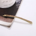Dettaglio molletta dorata per capelli con strass arancioni su sfondo di rivista - Champagne