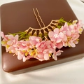 Detail shot of a pink floral hair fork with golden metal u-shaped pins on a brown box. - Hair Stick / Gold-Peach Pink