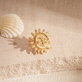 Detail of vintage gold sun earring with a face relief on textured stone backdrop - Clip Earring - Gold Sun Face