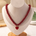 Elegant wine red pearl necklace featuring a gold-edged heart pendant on a display bust - Burgundy