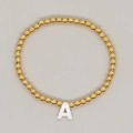 Golden beaded bracelet featuring a minimalist white resin alphabet letter A charm pendant - White Shell Letter A