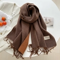 Detail of a brown and orange reversible cashmere scarf with fringes and logo label - Caramel color