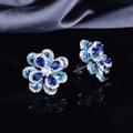 Detailed close-up of blue zircon flower earrings with silver studs on grey silk - Stud Earrings (Pair)