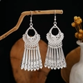 Close-up of silver boho ethnic earrings with hollow patterns and tassels on wood - Silver Hollow Pattern Multi-Row Tassel Style (E2873-9)