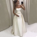Elegant strapless ivory satin wedding gown with a large waist bow and A-line skirt - US 2 / Ivory
