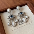 Detail view of silver earring featuring a blue eye motif with elegant white teardrop pearls - 59# Silver