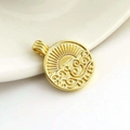Close-up of golden sun and wave embossed pendant on a white ceramic dish - Gold Plated Copper