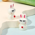 Close-up of small resin white bunny figurines with red hearts for DIY micro landscapes - Squinting Heart Rabbit