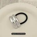 Minimalist black hair tie with silver double-arc metal clasp on a beige plate - Double Layer Arc Silver