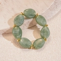 Detailed view of sage green acrylic marble beads with golden spacers on stone surface - Green