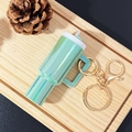 Green mini tumbler keychain with gold metal hook on a decorative wooden tray - Dazzling Green / Gold Buckle