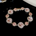 Nahaufnahme eines eleganten Armbands mit rosa Edelsteinen, Goldauflage und Kristallkranz - Armband-Gold-Rosa