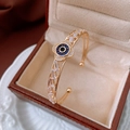 Detailed macro of a gold flower bangle with blue zircon stones on a beige velvet cushion - Gold