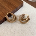 Dettaglio ravvicinato di orecchini a doppio cerchio placcati oro 18k con texture marrone - Marrone (Placcato Oro 18K)