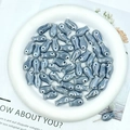 Macro shot of grey fish-shaped ceramic beads for DIY jewelry making on a white tray - Dark Gray