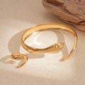 Vista dettagliata del set bracciale e anello a serpente dorato su sabbia dalla texture naturale - Bracciale + Anello / Serpente d'Oro (Set da 2 pezzi)