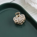 Golden heart-shaped hair claw clip with clear rhinestones on a dark green tray - Rhinestone Style (c5221)