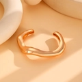Close-up of gold geometric wave-shaped alloy bangle with polished irregular surface - Irregular Wavy Bangle (4347) / Gold