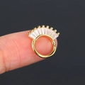 Anello per setto nasale dorato con pietre di zircone rettangolari tenuto tra le dita - Oro
