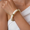 Detail der runden cremefarbenen Acrylsegmente und goldenen Metallkugeln des Armbands - Weiß