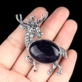 Silver elk brooch with oval dark blue sandstone held in palm for size scale - Blue Sand Stone (Synthetic)