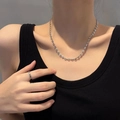 Detail van een minimalistische zilveren koffieboon ketting en eenvoudige ringenset bij model - Zilveren Ketting