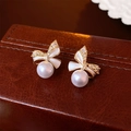 Close-up of gold-plated bow earrings with creamy pearls and shimmering cubic zirconia - Gold Bow Pearl Style