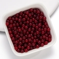 Polished deep red round glass beads in a white bowl for DIY Christmas jewelry making - Glass Faux Jade Bead - Deep Red
