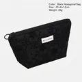 Black hexagonal makeup bag with floral embossed texture and white woven label - Hexagonal Bag / Black Hexagon Bag