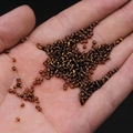 Amber color glass seed beads in 2mm size held in palm for DIY jewelry making - 2mm / 15g / Coffee