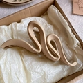 Macro detail of a large wavy acrylic hair claw clip with matte finish in light brown color - Khaki