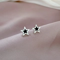 Nahaufnahme der Stern-Ohrstecker aus Titanstahl auf rosa Satin mit schwarzer Emaille - Stahlfarbe