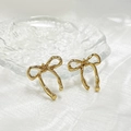 Macro shot of elegant golden bow stud earrings on a textured decorative glass plate - Gold Ribbon Bow