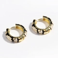 Macro shot of gold-plated hoop earrings with black enamel and white flower patterns - Black