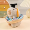 Plush capybara doll with graduation cap and blue donut ring in a cozy indoor setting - Donut / White