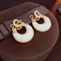 Dettaglio orecchini vintage dorati a cerchio intrecciato con smalto bianco su velluto - Stile Smaltato Bianco Anello Intrecciato Oro