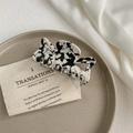 Close-up of black and white marble acetate hair claw clip on a ceramic display dish - Cow Print