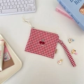 Close-up of a red checkered coin pouch with cherry embroidery on a desktop background - Cherry