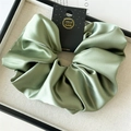 Close-up of sage green satin scrunchie with smooth silk texture and handmade card - 18cm / Dark Green