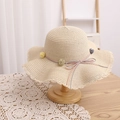 Detailed close-up of straw sun hat featuring wavy openwork edges and pom-pom floral trim - Beige Hat
