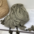 Detail of grey-green cotton linen scarf featuring hand-made tassels and striped wooden beads - Green