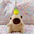 Cute Capybara plush keychain with small yellow pineapple hat on a colorful background - Light Brown Pineapple + Gold Clip