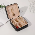 Detail showing the black leather jewelry box with beige velvet lining and zip closure - 10*10*5 / Black